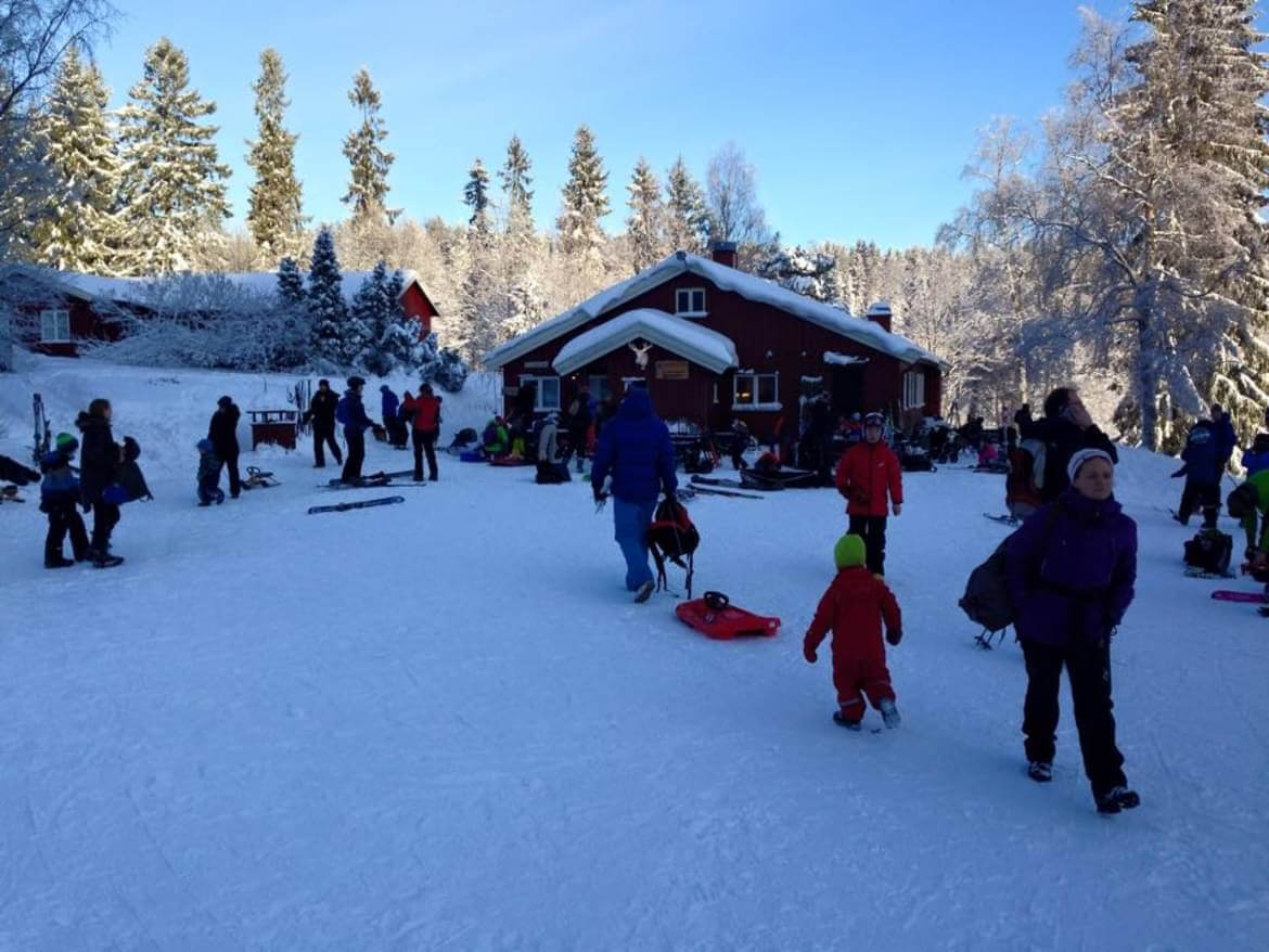 Vinterdag ved skianlegget med varmestue og familier i området